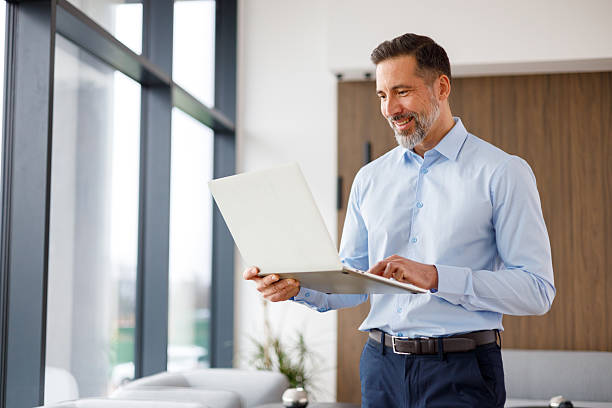 istock Happy mid adult man working remotely on a laptop, using wireless technology for business tasks in an office interior 2249023762