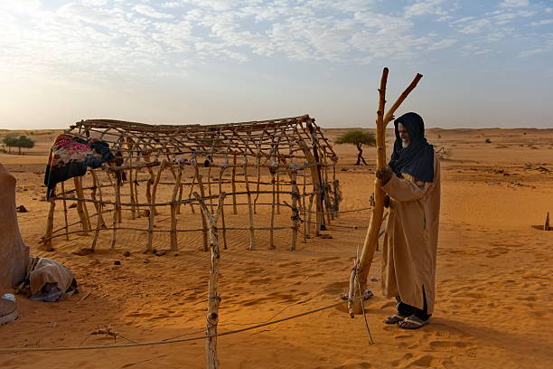 Shinguetti, Mauritania. October 04, 2021. Portrait of an elderly, bearded Mauritanian in national dress (derra) with a wooden stick, from which nomads of the Sahara Desert make temporary housing.