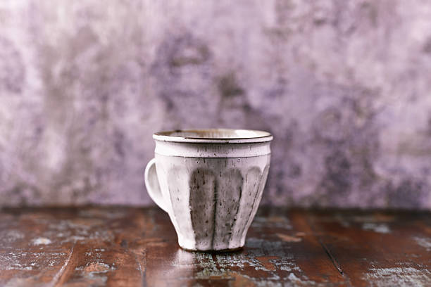 Person holding ceramic cup with blurred background, cozy ambiance, minimalist home decor, warm beverage