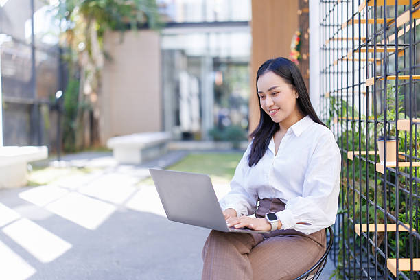 istock Young Asian woman working on laptop outdoors at cafe 2249032187