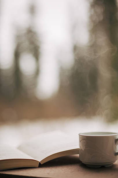 istock Steaming coffee mug next to open book indoors 2249039109