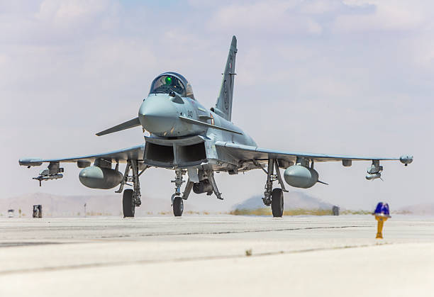 A powerful military jet fighter positioned on a runway, ready for takeoff under a clear sky.