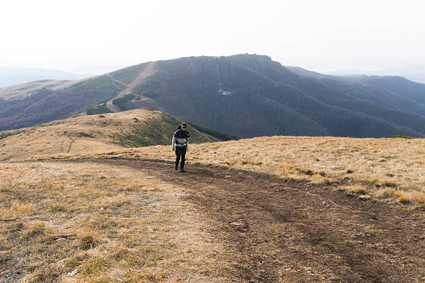 istock Man climbing the mountain in autumn yellow grass field 2249042048