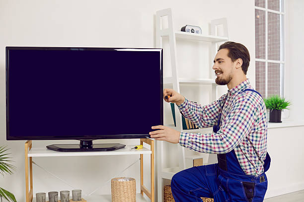 istock Young repairman or technician fixing or installing a modern large television set at home 2249047261