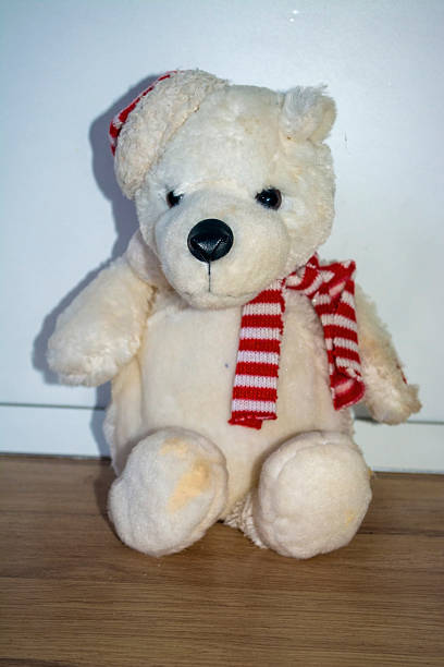 A cute white plush teddy bear wearing a festive red and white striped hat and matching scarf. Perfect for Christmas decorations, holiday-themed designs, and cozy seasonal backgrounds