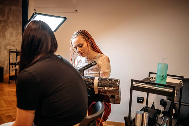 istock Woman working in tattoo studio on customer arm 2249049571