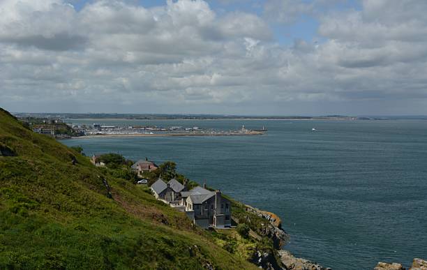 istock Scenic Coastal View With Lush Green Hills and a Peaceful Harbor Under a Bright Sky 2249050035