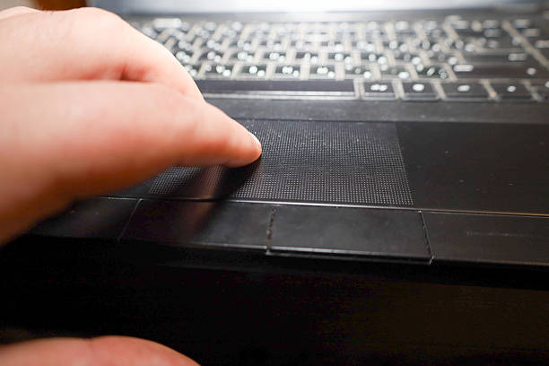 istock A fragment of a black laptop in close-up: a user's hand touches the touchpad panel, using it to control the computer. The image emphasizes human and technology interaction in a work process or study. 2249052982