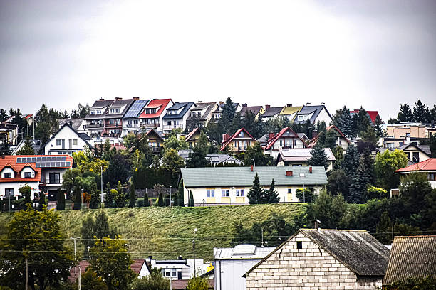 Hillside covered with residential houses featuring colorful roofs and solar panels surrounded by green trees.