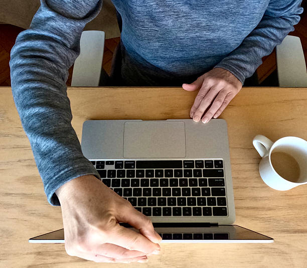 EX High angle MCU woman open or closes laptop computer at office desk with coffee cup