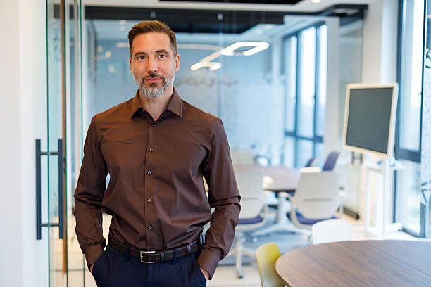 istock Experienced businessman posing with hands in pockets at a bright modern office. Concepts of leadership, confidence, and professionalism 2249069074