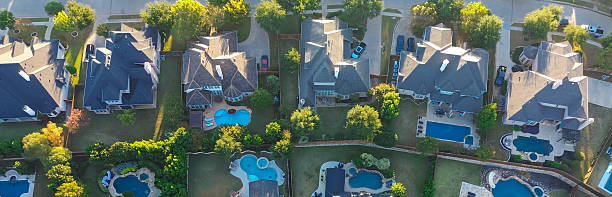 istock Panorama aerial grid-patterned Lantana neighborhood with tree-lined streets, upscale mansion homes, backyard pools, captured in warm light with long shadows and architectural uniformity, Texas 2249071719