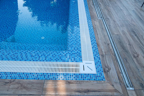 istock Swimming pool showcasing blue mosaic tiles, clear water reflecting light, plastic overflow drainage system, and wooden deck flooring providing a clean, inviting atmosphere for summer relaxation 2249075776