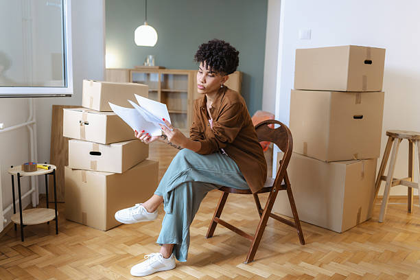 istock Young woman reviewing documents while surrounded by moving boxes in a new apartment 2249079574