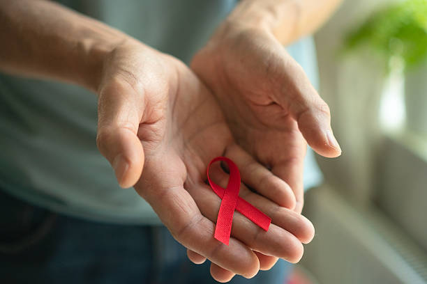 istock Mans Hands Presenting Red HIV AIDS Awareness Ribbon 2249081789