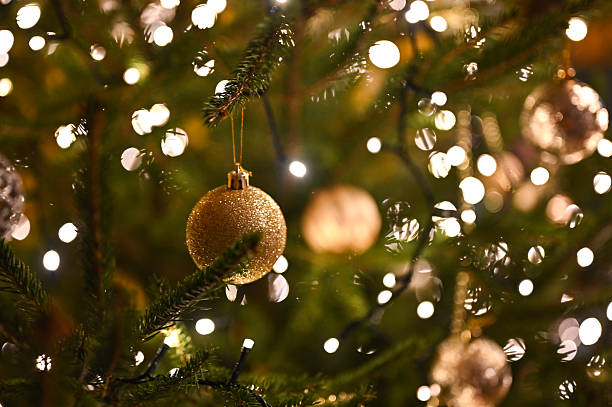 istock Gold christmas ornament hanging on tree with lights 2249081853