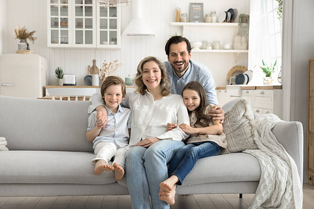 istock Family with two kids relaxing on sofa looking at camera 2249082621