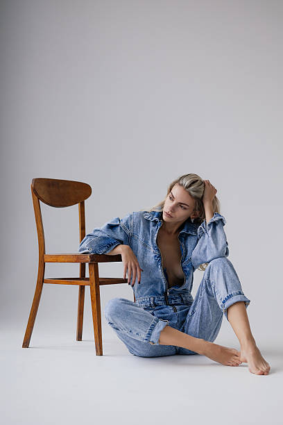 istock Blonde Woman in Denim Jumpsuit Posing Casually in Studio 2249083565