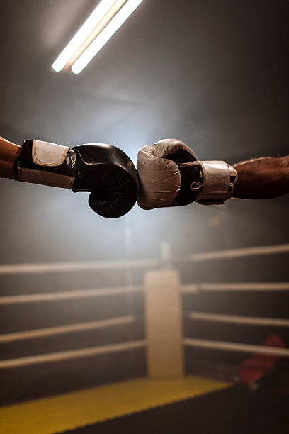 Boxer wearing boxing gloves and a head guard practices punches during training, preparing for competition with focused determination