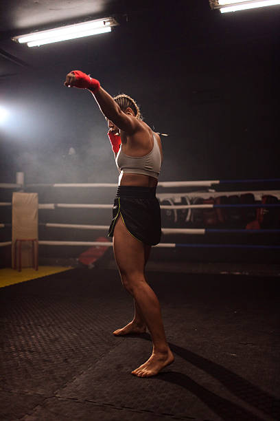 istock Female boxer training in dim gym with red gloves 2249084024