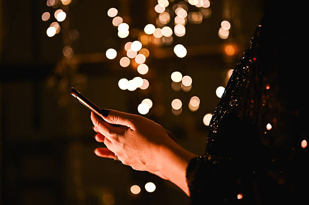 istock Woman holding phone at night with bokeh lighting 2249086090