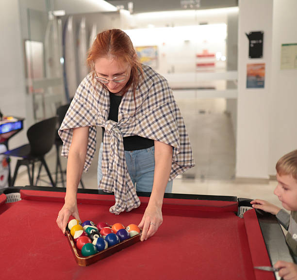 istock Woman racking billiard balls teaching child game 2249089061