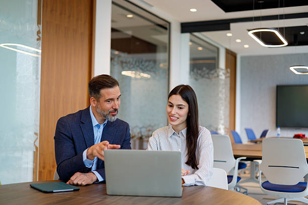 istock Two diverse business colleagues working together on a laptop in a modern office, planning strategies for growth 2249090356