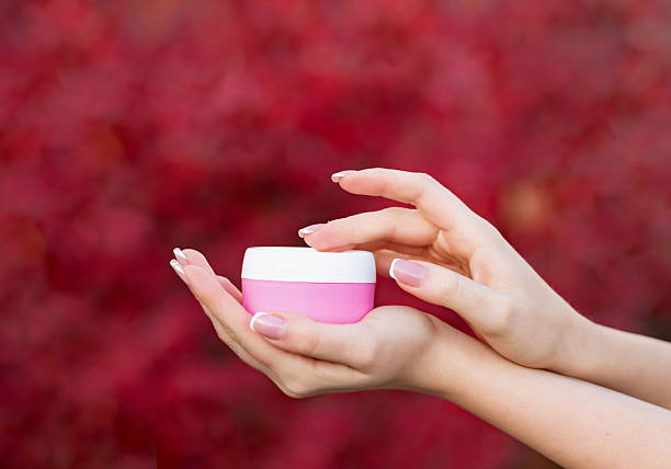 istock hands holding and applying cream jar for skincare 2249095176