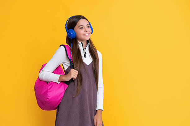 istock smiling child in headphones with school backpack on yellow background 2249095286