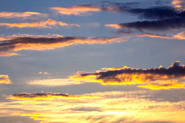 The sky displays a breathtaking array of colors during sunset, with golden, orange, and purple hues blending through the clouds. This stunning view captures the tranquility of the evening sky.