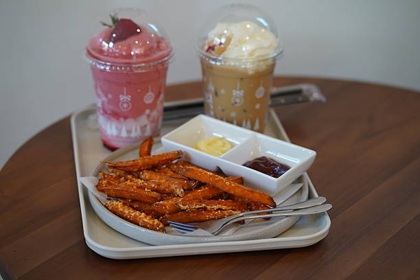 Delicious Sweet Potato Fries Served with Dipping Sauces Alongside Colorful Beverages on a Wooden Table in a Cozy Café Setting