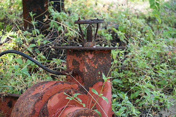 istock Old rusted sprinkler system overgrown with weeds in a neglected garden setting, providing a sense of decay 2249118071