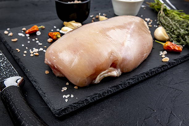 istock Fresh chicken breast on a black cutting board with herbs and spices ready for preparation in a kitchen setting 2249118817