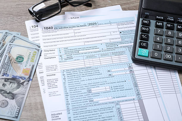 istock Payroll. Tax return forms, dollar banknotes, glasses and calculator on wooden table 2249118892