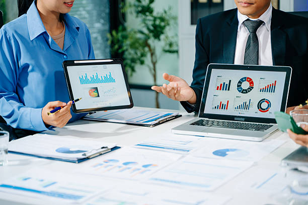 istock Businessman hand using smartphone, laptop and tablet with social network diagram and team colleagues discussing data on desk as concept i 2249124068