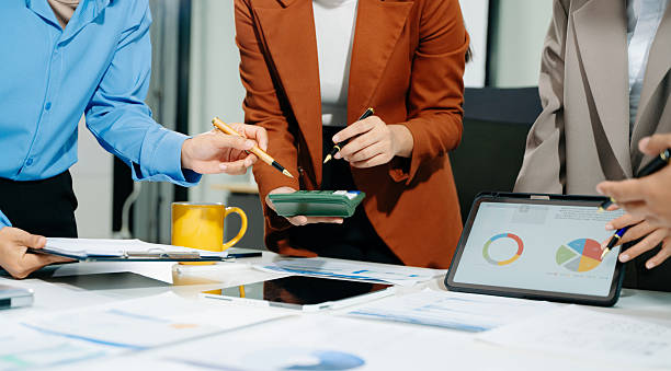 istock Business documents on office table with smart phone and laptop and team colleagues discussing data 2249124124