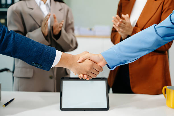 Young Asian business team joins hands in unity, symbolizing teamwork, collaboration, and success in a modern office. Perfect for business, motivation, and leadership themes.