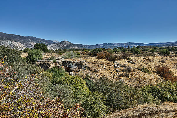 istock Arid valley with sparse vegetation and rocky formations, set beneath distant mountain peaks and open blue sky 2249125835