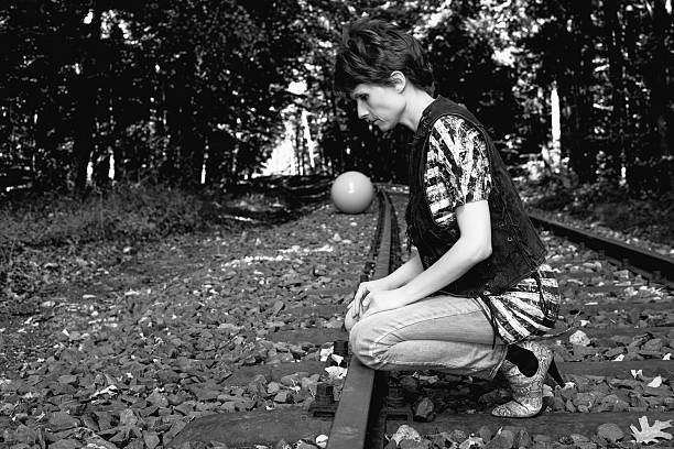 girl with pigtails walk on rails with a balloon on a string in her hand