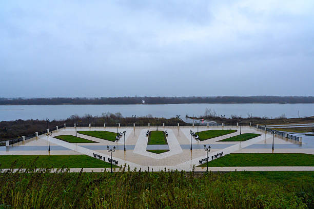 Murom, Russia - November 4, 2025: Lush greenery frames the riverside park in Murov, where pathways meet tranquil waters under a serene, cloudy sky, inviting peaceful strolls and relaxation.