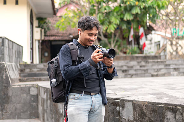 istock Indonesian photographer walking with camera and backpack outdoors 2249130813