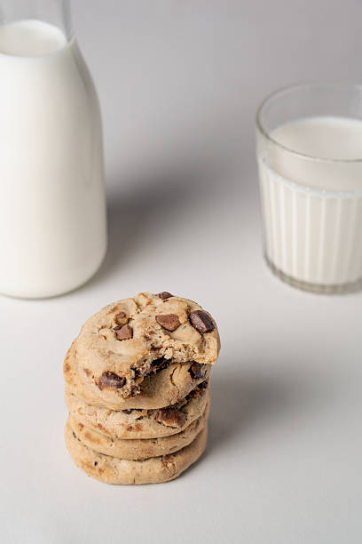 Stack of cookies between a blurred bottle and glass of milk