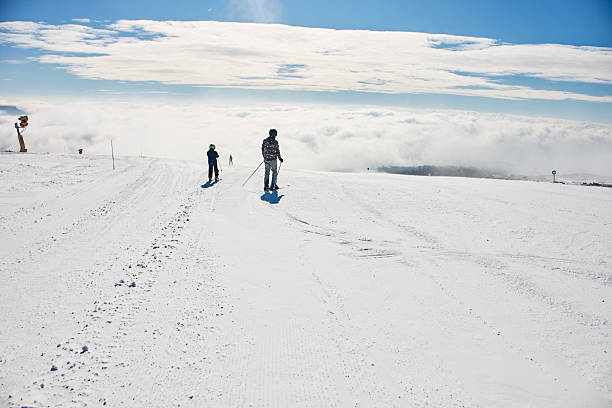 Two people skiing on a sunny winter day with a picturesque cloudy sky