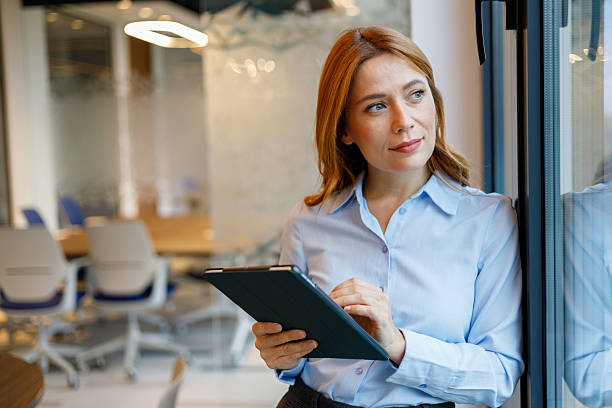 istock Thoughtful businesswoman using digital tablet in modern office, finding inspiration looking out window 2249133433