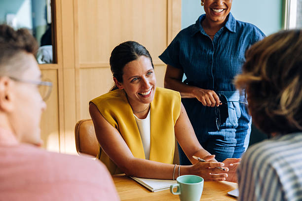 istock Smiling woman discussing ideas with colleagues around a table 2249134312