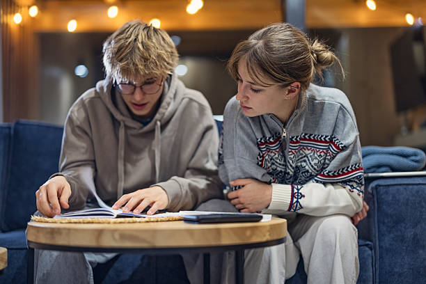 istock Teenagers study together indoors, surrounded by warm light and string-lit atmosphere 2249135213