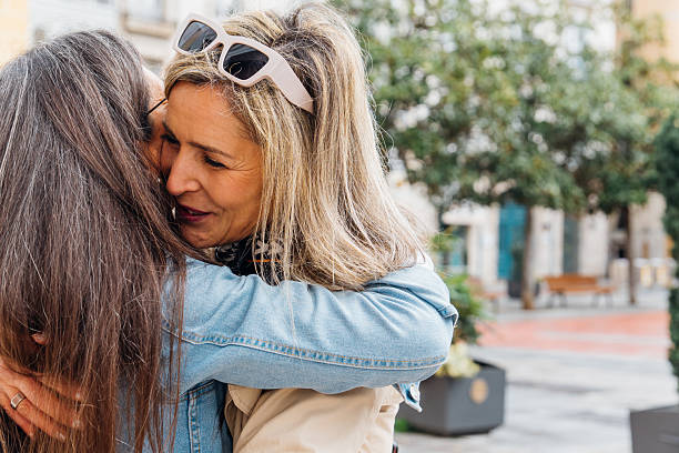 istock Mature friends embracing emotionally outdoors, two women showing affection and connection during a warm hug in a vibrant city square, celebrating long-lasting friendship 2249142769