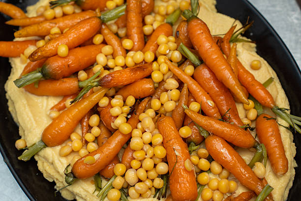 Delicious Roasted Baby Carrots and Chickpeas Served Over Creamy Hummus in a Black Platter