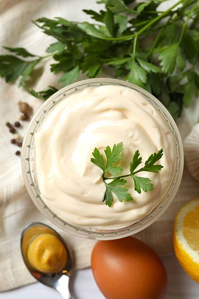 Bowl with mayonnaise and ingredients for cooking on the table
