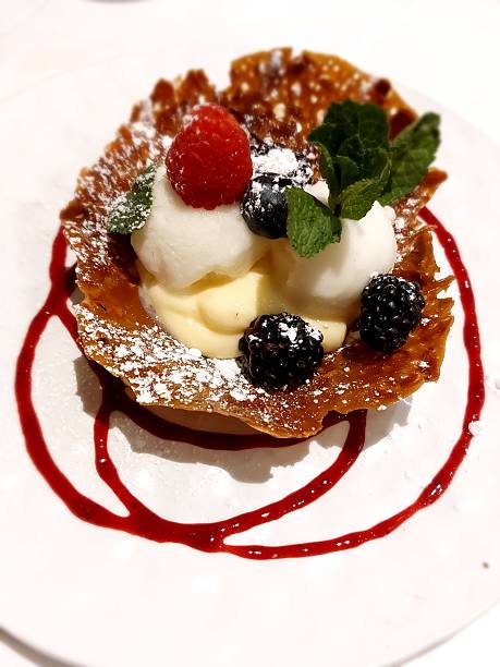 Ice cream scoop dessert in a crispy waffle topped with strawberry, raspberry and mint leaf. Valladolid, Castile and León, Spain, Europe - March 24, 2024.